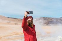 Mann steht mit Smartphone am Geysir — Stockfoto
