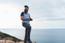 Mann hält Fotokamera an Küste — Stockfoto