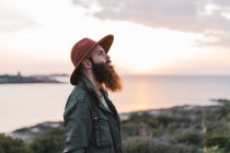 Задумчивый бородатый человек стоит на берегу моря — стоковое фото