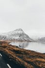Скелястий хребет у снігу над озером — стокове фото