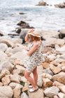 Donna con cappello in piedi sulle rocce — Foto stock