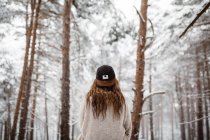 Mulher usando boné na floresta nevada — Fotografia de Stock