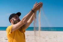 L'uomo versa sabbia sulla spiaggia — Foto stock
