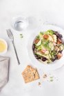 Вкусный свежий овощной салат с крекерами на белом столе. — стоковое фото