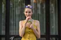 Woman in summer dress standing with drink — Stock Photo