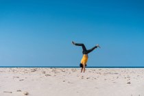 Uomo che fa stand sulla spiaggia di sabbia — Foto stock
