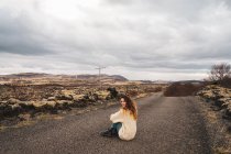 Mujer sentada en el camino en la naturaleza rocosa - foto de stock