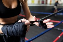 Mujer de fitness en ropa deportiva enroscando vendaje de boxeo - foto de stock