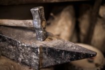 Ritaglio vista ravvicinata del martello sdraiato su incudine metallica in fabbrica di colata — Foto stock