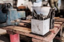 Vue en coupe du marteau et des instruments sur la table métallurgique en bois — Photo de stock
