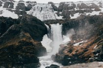 Водопад, текущий из мрачных черных камней — стоковое фото