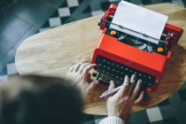 Persona sosteniendo la pluma y escribiendo en la máquina de escribir - foto de stock