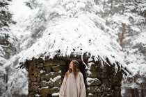Жінка стоїть біля хатини в зимовому лісі — стокове фото