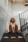 Смеющаяся женщина, сидящая на потрепанных ступенях — стоковое фото
