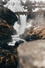 Wasserfall fließt aus düsteren schwarzen Felsen — Stockfoto