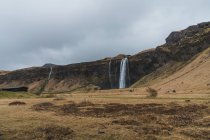 Wasserfall und Klippen unter stürmischem Himmel — Stockfoto