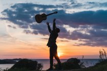 Hombre divirtiéndose con la guitarra en la costa - foto de stock