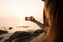 Femme prenant des photos au bord de la mer — Photo de stock