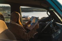 Homem sentado no carro e segurando mapa — Fotografia de Stock