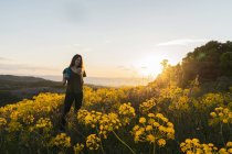 Donna utilizzando smartphone tra i fiori selvatici — Foto stock