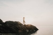 Donna in piedi sulla roccia costiera — Foto stock