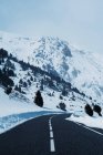 Strada vuota nelle montagne innevate — Foto stock