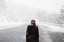 Femme marchant sur la route enneigée — Photo de stock