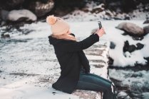 Donna che prende selfie al fiume in inverno — Foto stock