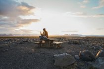 Donna seduta sul tavolo di legno al tramonto — Foto stock