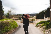 Woman in black walking on road in countryside — Stock Photo