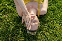 Mujer acostada sobre hierba y cubierta de rostro - foto de stock