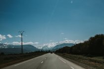 Perspective view to asphalt road leading through nature to snowy mountains in Morocco. — Stock Photo