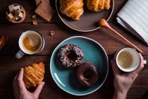 Mãos com café e croissant — Fotografia de Stock