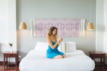 Жінка використовує смартфон на ліжку — стокове фото