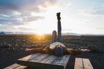 Жінка лежить на дерев'яному столі на заході сонця — стокове фото