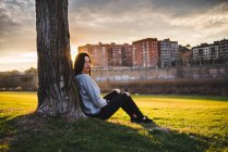 Frau sitzt unter Baum im Sonnenlicht — Stockfoto
