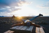 Жінка лежить на дерев'яному столі на заході сонця — стокове фото