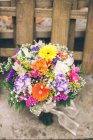 Bouquet de différentes fleurs colorées sur table et vélo sportif à l'intérieur. — Photo de stock