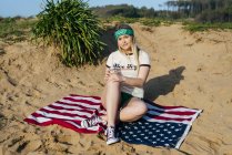 Menina com bebida sentado na bandeira americana — Fotografia de Stock