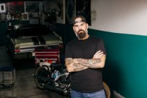 Tätowierter Mechaniker steht in Garage — Stockfoto