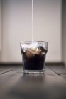Latte versando nel caffè freddo ghiacciato — Foto stock
