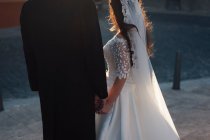 Mano dello sposo irriconoscibile che abbraccia la sposa in abito bianco. — Foto stock