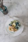 Hochzeitstorte mit blauen und beigen Buttercremeblüten auf weißem Teller — Stockfoto