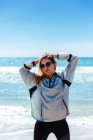 Donna in occhiali in piedi sulla riva del mare — Foto stock