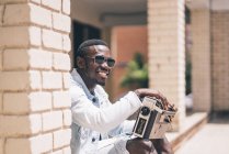 Smiling black man in sunglasses holding vintage radio device outdoors — Stock Photo