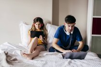 Пара використовує гаджети в ліжку — стокове фото