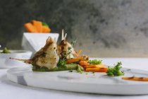 Риба на грилі з горошком і морквяними паличками на мармуровій тарілці — стокове фото