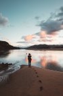 Back view of photographer on sandy beach of Laida with colorful sky reflecting in water, Bizkaia — Stock Photo