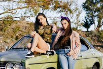 Frauen posieren vor grünem Auto — Stockfoto