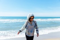 Жінка в окулярах ходить на березі моря — стокове фото